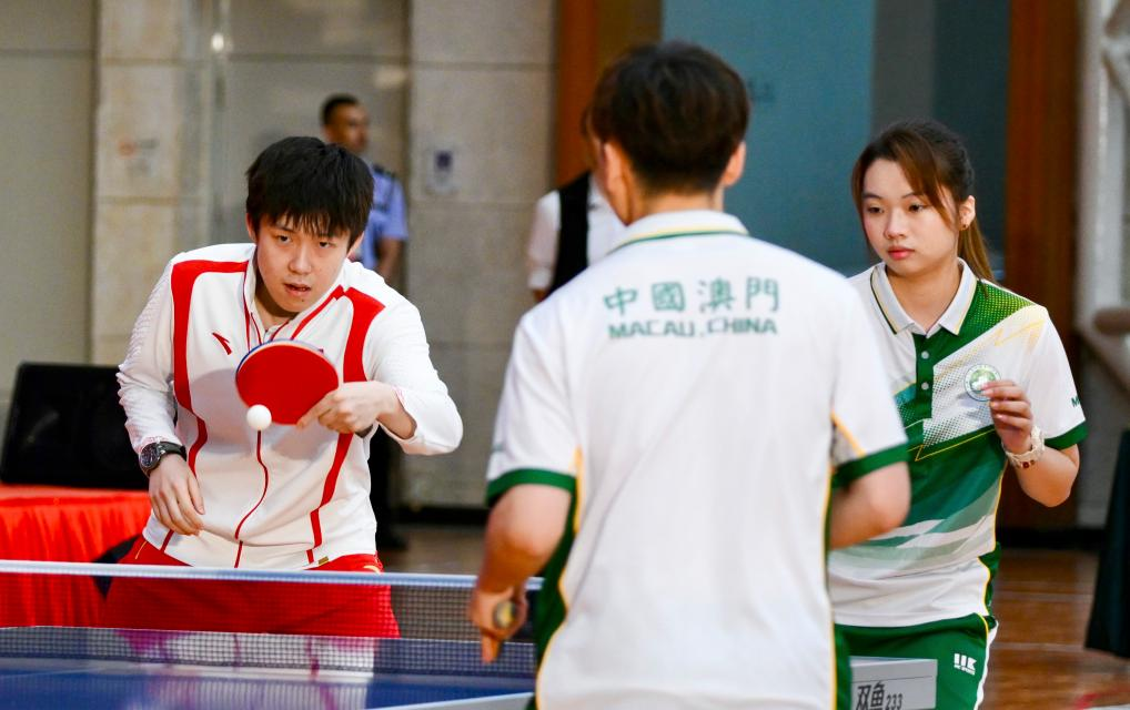 9月1日，乒乓球運動員王楚欽（左）與澳門運動員切磋球技。當日，內地奧運健兒代表團在澳門奧林匹克體育中心室內體育館與澳門青少年運動員進行互動交流。新華社記者 郭雨祺 攝
