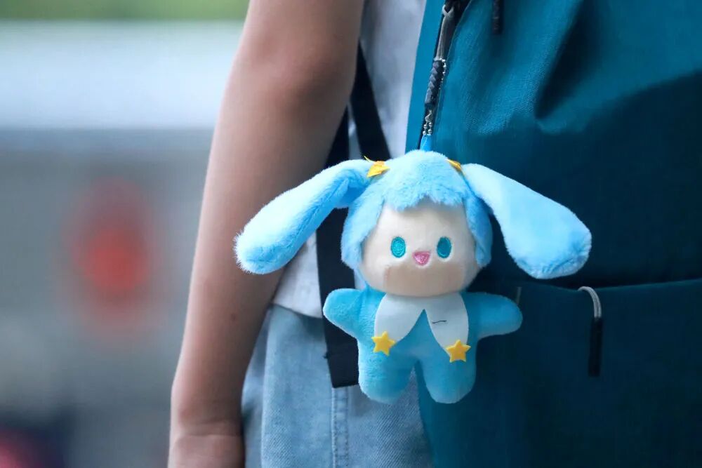 “包掛” 風(fēng)潮正悄然席卷年輕群體，有人背包側(cè)面掛個小玩偶。