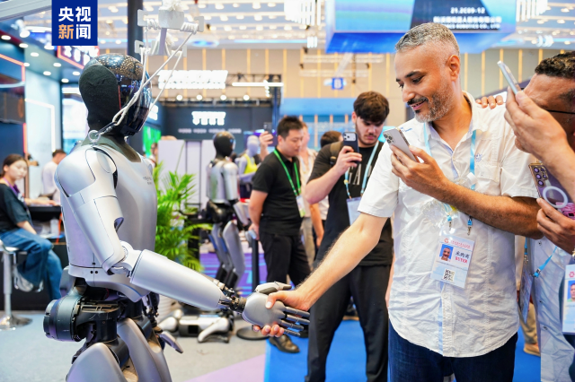 廣交會現場,參會人員正與機器人握手互動。 廣交會現場,參會人員正與機器人握手互動。