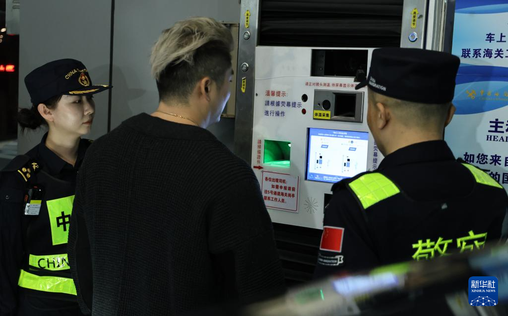 12月23日，“粵車南下”入境香港市區(qū)的首位通關(guān)車主彭先生（中）在“一站式”通道辦理通關(guān)手續(xù)。新華社記者 黃國保 攝