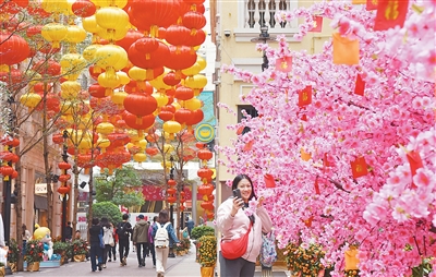 圖為一名女士在香港利東街與新春裝飾“桃花樹”自拍合影。新華社記者 陳 鐸攝